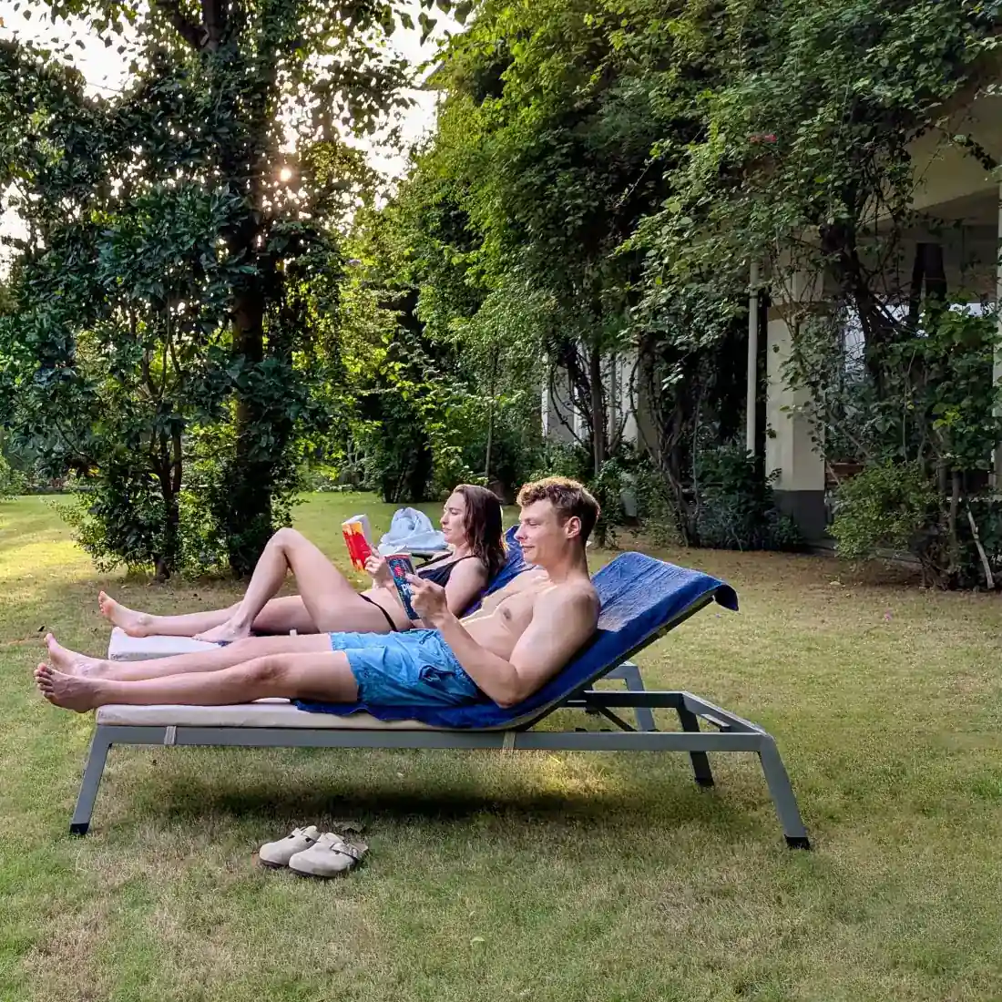 Two guests reading quietly on loungers in the late-afternoon garden