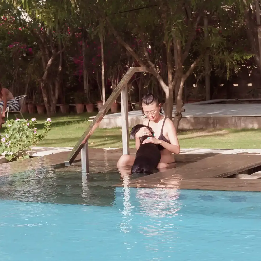 A guest sitting quietly with a farm dog at the pool