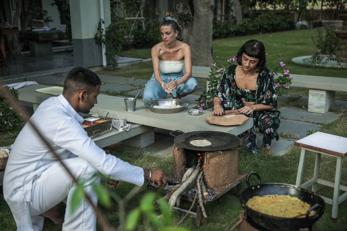 A cooking class with guests around the fire