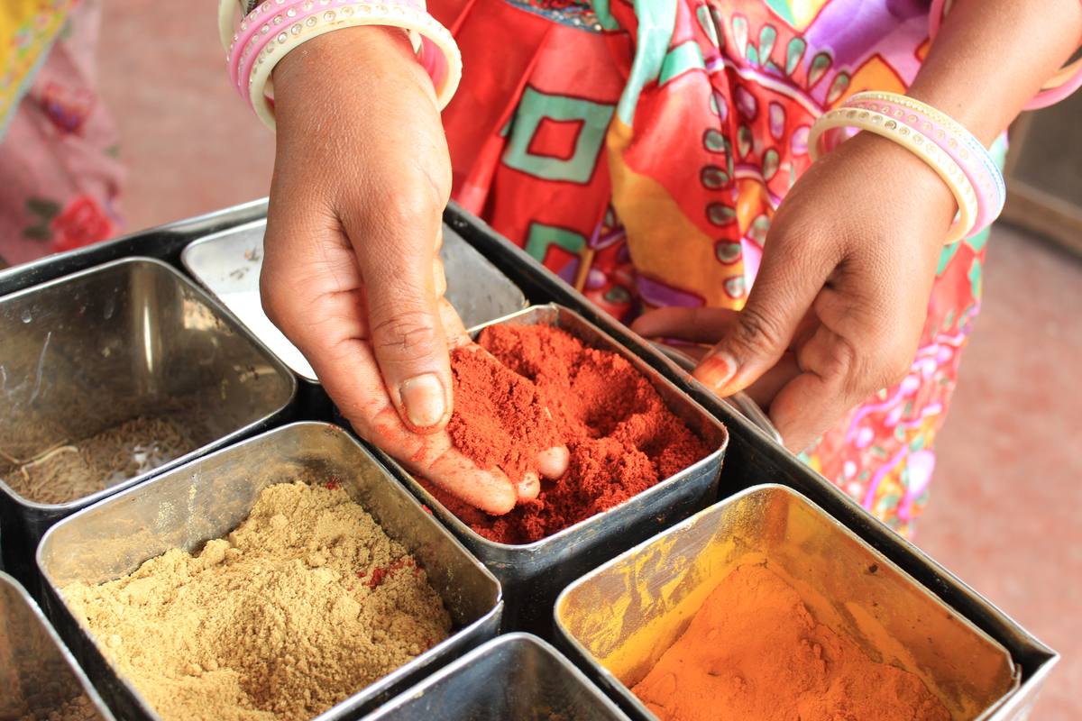 Hands adding spice while cooking