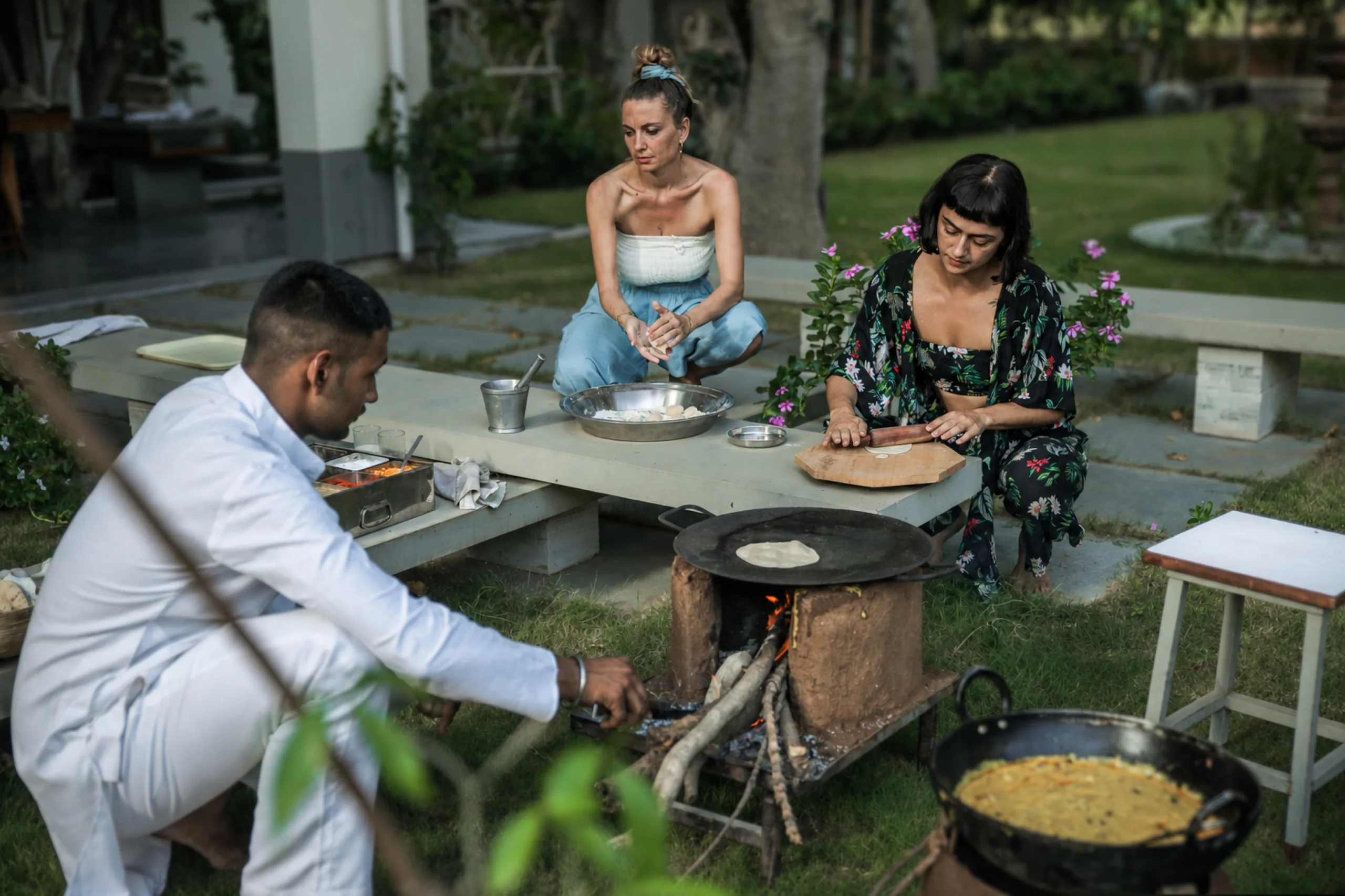 Vish tending the wood fire while guests make rotis and kadhi in the garden