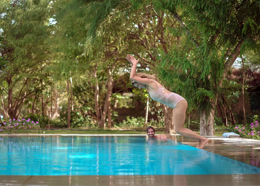 Woman diving into the pool while a man watches from the water