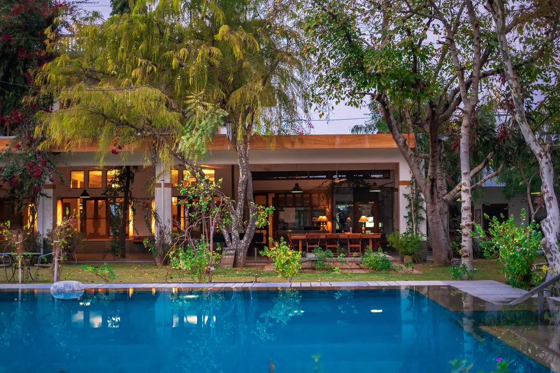 The illuminated farm building and trees reflected in the pool at dusk