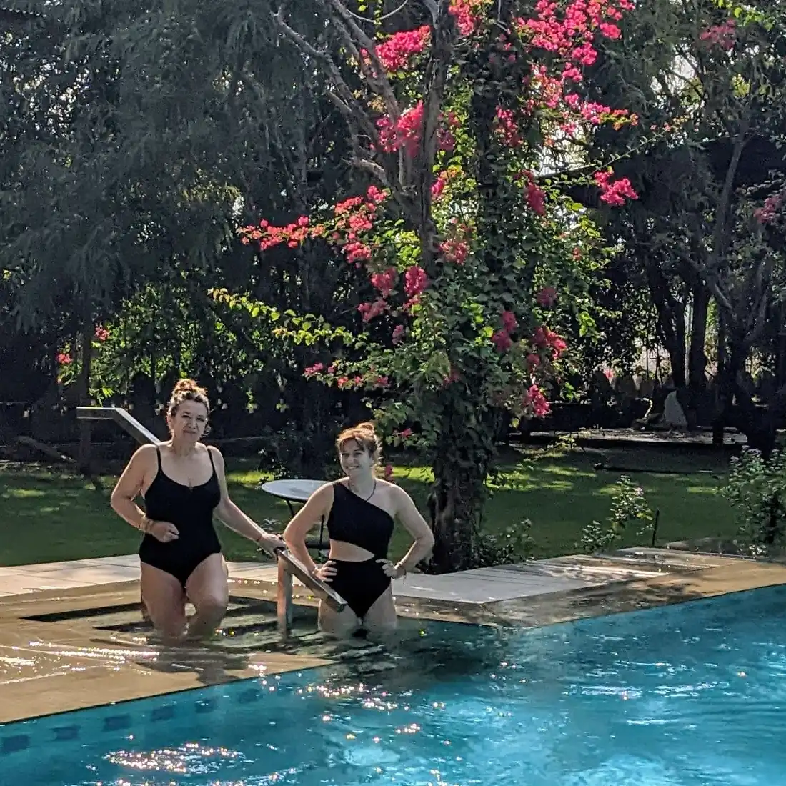 Guests stepping into the pool beneath a blooming bougainvillea tree