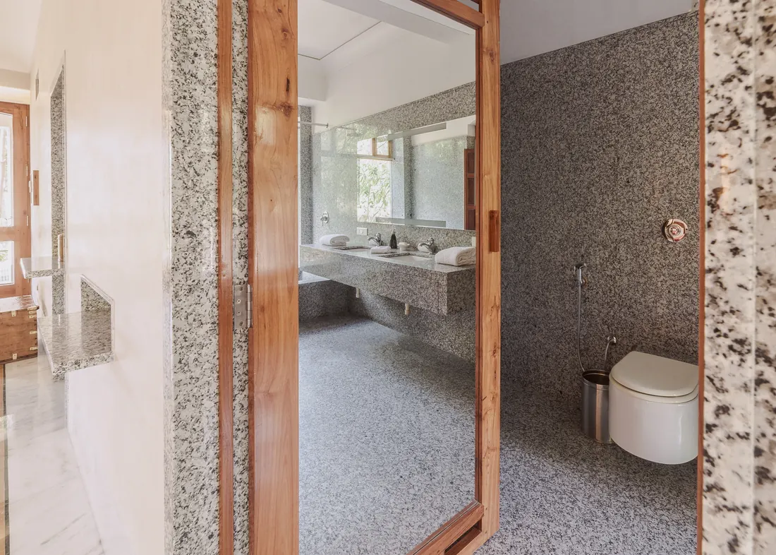 The Suite bathroom entrance, double sinks, granite walls, and toilet