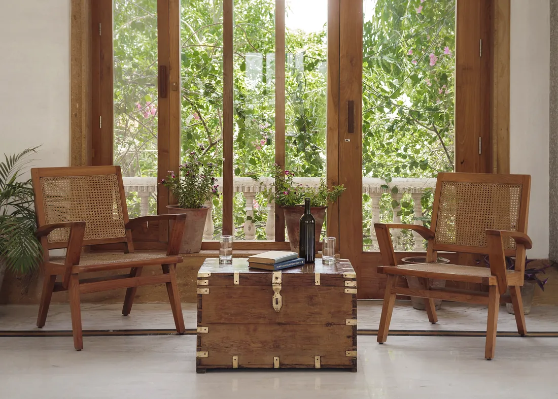 Two cane chairs, an antique trunk, and garden filling the Suite window