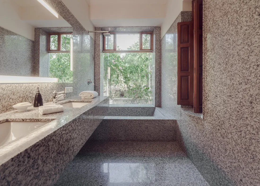 Granite bathroom with sunken tub facing a bougainvillea-framed window